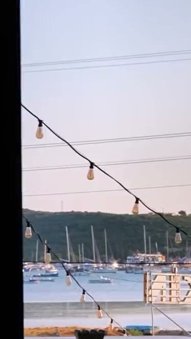 Balkondan akşam: ampul zinciri, marina ve körfez.