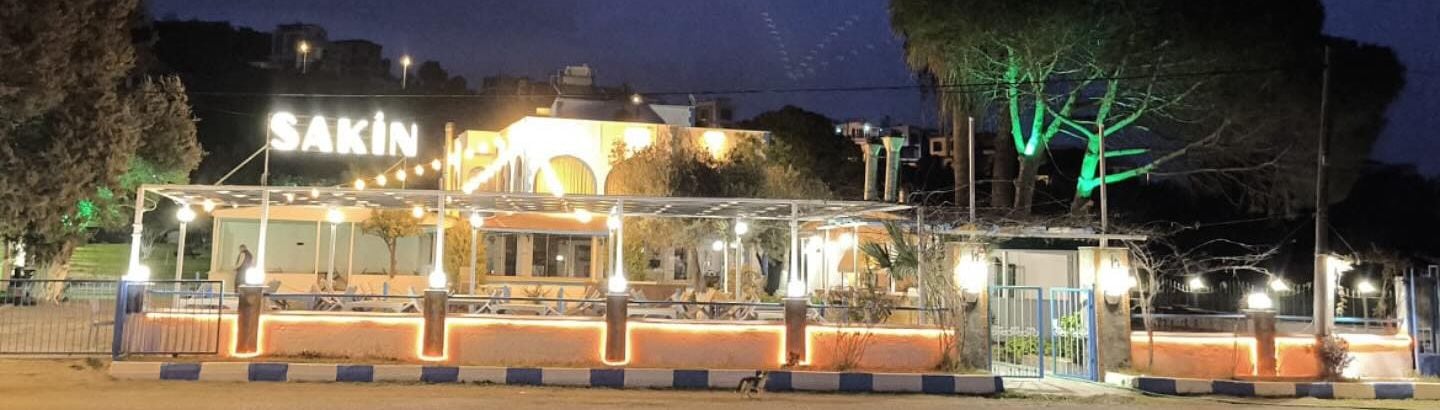 Gece, ışıklı tabela ve terasın önü.